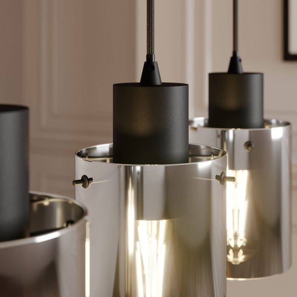 Detailaufnahme von modernen Pendelleuchten mit zylindrischen Glasschirmen in Chromoptik, schwarzen Fassungen und Filament-Leuchtmitteln.