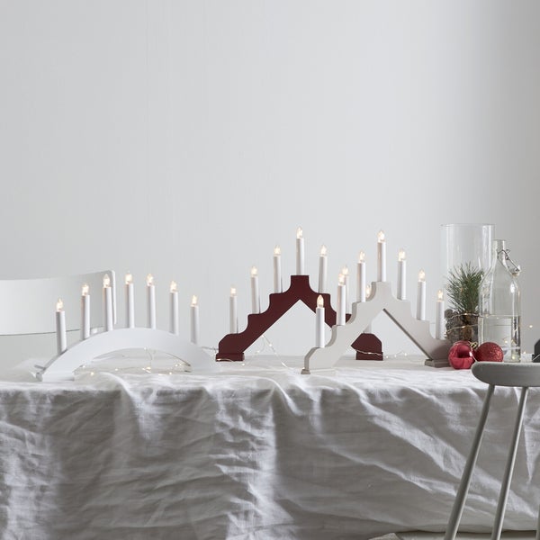 Dekorativer Tisch mit hölzernen Lichterbögen und Weihnachtsschmuck für eine festliche Atmosphäre