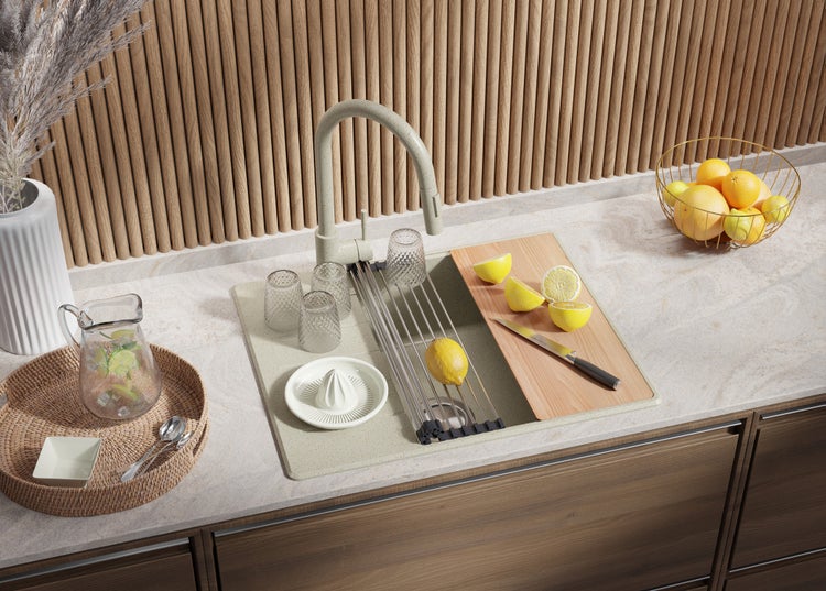 Küchenszene mit Spüle, Armatur, Schneidebrett, Zitronen, Gläsern und Karaffe
