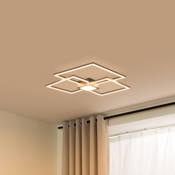 Moderne LED-Deckenleuchte im geometrischen Design aus drei überlappenden Quadraten, warmes Licht, montiert an der Decke über einem Fenster.