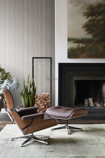 Wohnzimmer mit Sessel und Fußhocker, Kamin und Dekorationselementen für ein gemütliches Ambiente