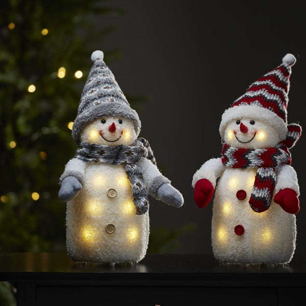 Zwei beleuchtete Schneemannfiguren mit Mützen und Schals als Weihnachtsdekoration