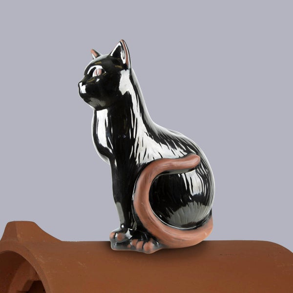 Firstfigur Katze in Schwarz aus glasiertem Ton auf einem Firstziegel.