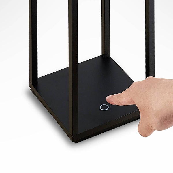 Nahaufnahme eines Berührungssensors am Sockel einer schwarzen Außenleuchte, der mit einem Finger bedient wird.