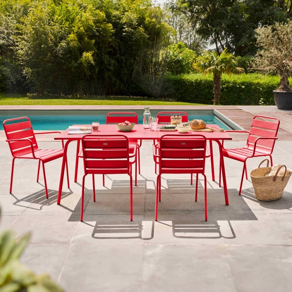 Moderne rote Garten-Essgruppe aus Metall mit rechteckigem Tisch und sechs Stühlen auf einer Steinterrasse an einem Pool.