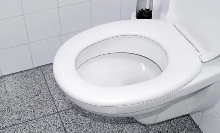 Hängendes Wand Tiefspül WC mit offenem Spülrand und WC Sitz montiert in einem Badezimmer mit Fliesen.