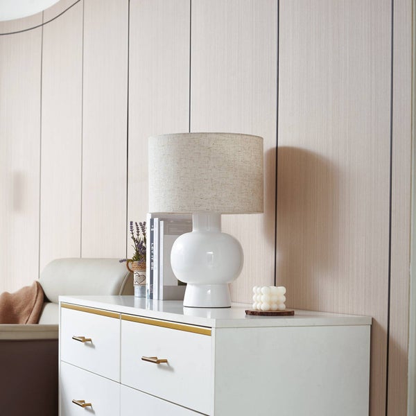 Dekorative Szene mit einer weißen Kommode, einer Tischlampe, Büchern und einer Pflanze