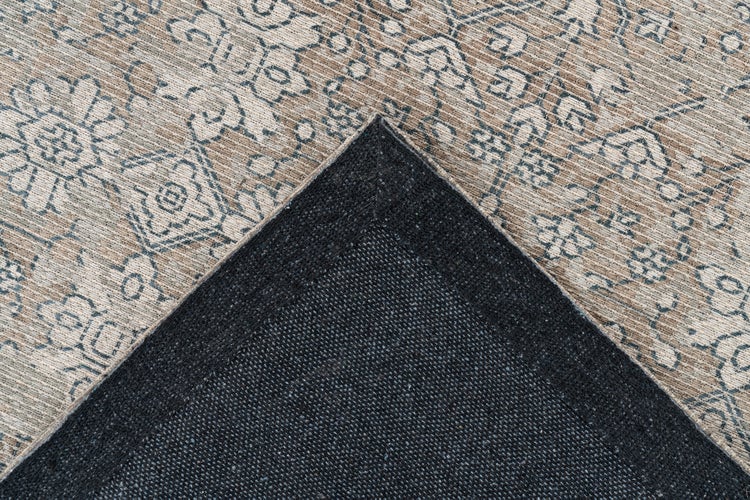 Nahaufnahme eines Teppichs im Vintage-Stil mit floralem Muster und strukturierter dunkler Rückseite.