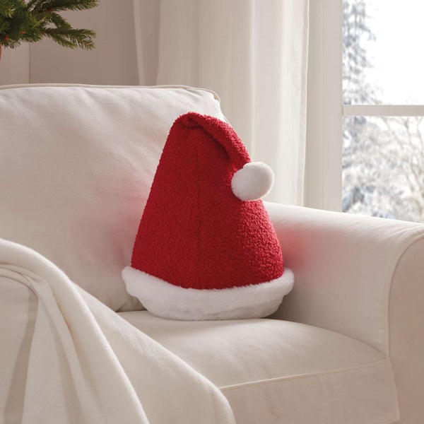 Dekoratives Weihnachtsmannmützen-Kissen auf einem Sessel