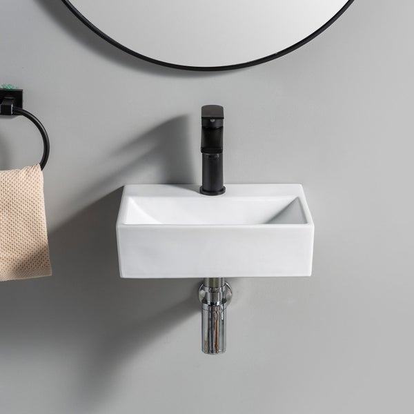 Wandwaschbecken aus Keramik mit Armatur und Handtuchhalter an einer Wand mit Spiegel.