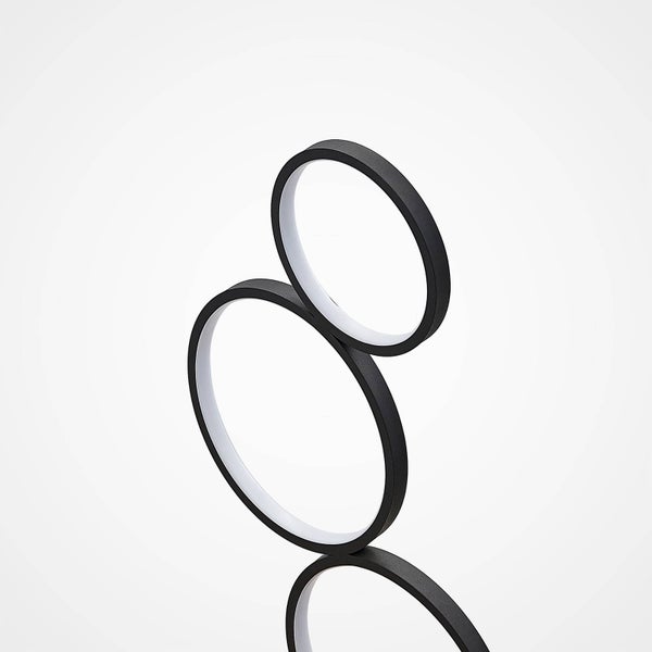 Nahaufnahme einer LED-Leuchte mit schwarzen, ineinandergreifenden Ringen aus Metall und Kunststoff.