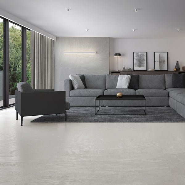 Modernes Wohnzimmer mit groáflächigen Bodenfliesen in Steinoptik, groáem Sofa, Sessel und dezenter Wandbeleuchtung in schlichtem Interieur.