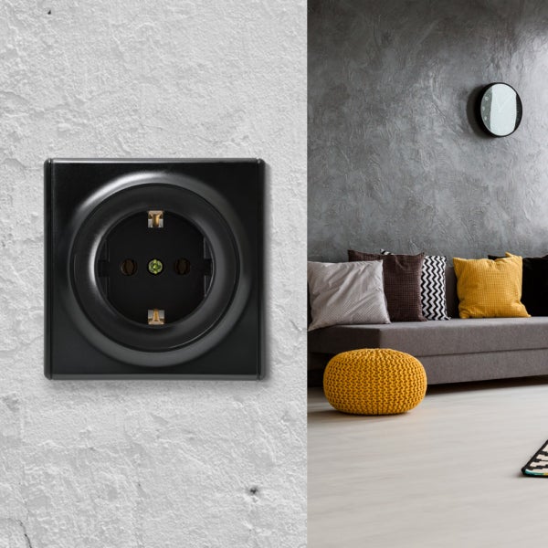 Schutzkontaktsteckdose in modernem Design an einer Wand montiert mit angrenzendem Wohnraum im Hintergrund.