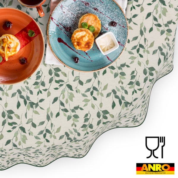 Tischdecke mit grünem Blättermuster, eingedeckt mit Frühstückstellern, ANRO Logo und Symbol für Lebensmittelechtheit.