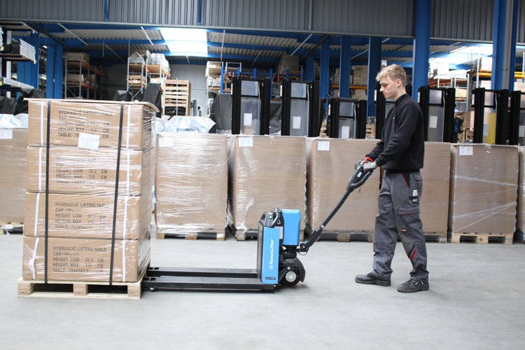 Mitarbeiter bedient einen elektrischen HanseLifter Hubwagen beim Transport einer Palette mit Kartons in einem hellen, organisierten Lager.
