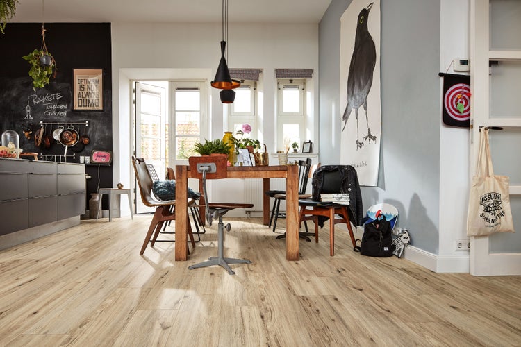 Wohnliches Esszimmer mit hellem Laminatboden in Holzoptik, Holztisch, verschiedenen Stühlen, Wandtafel und großen Fenstern.
