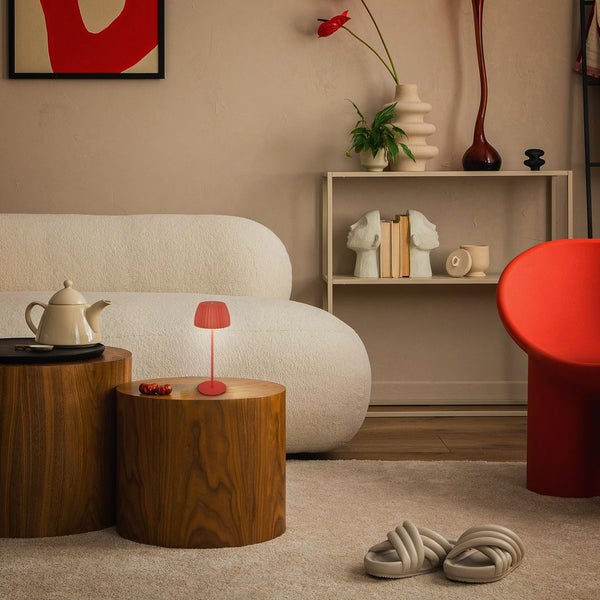 Wohnzimmer-Szene mit Sofa, Tischleuchte, Beistelltischen und dekorativen Elementen