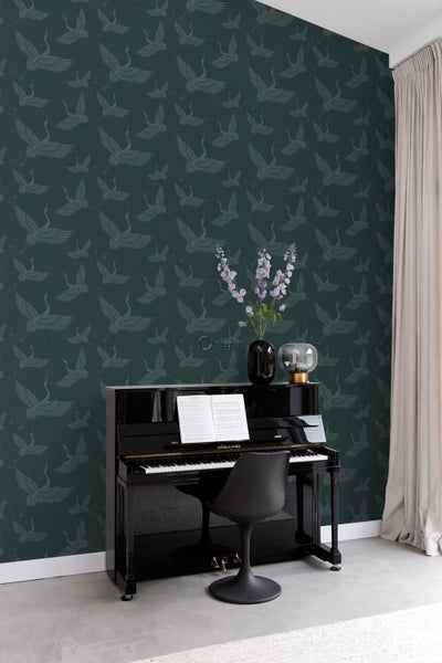 Raumansicht mit Tapete mit Kranichmuster, Klavier, Stuhl und Blumenvase.