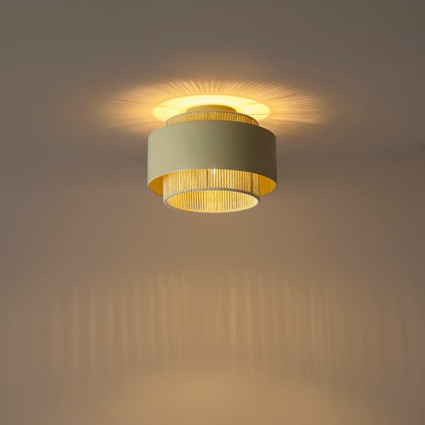 Moderne Deckenleuchte mit zweistufigem Schirm, warmem Lichteffekt und Strahlenmuster an Decke und Wand.