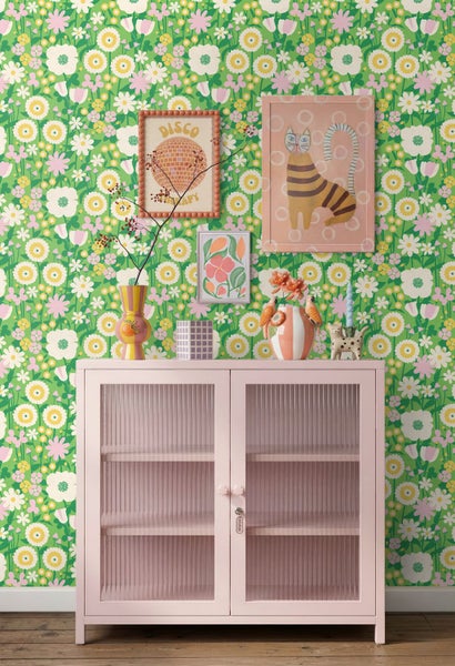 Vliestapete mit buntem Blumenmuster hinter einer rosa Vitrine mit geriffeltem Glas und Dekorationsgegenständen.