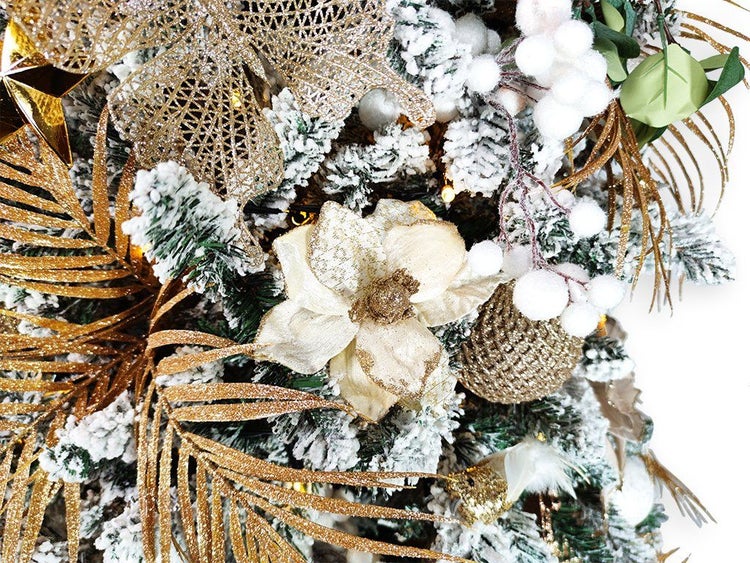 Festlich geschmückter Weihnachtsbaum mit künstlichen verschneiten Zweigen, goldenen Blumen, Sternen und weißen Beeren als Weihnachtsdekoration.