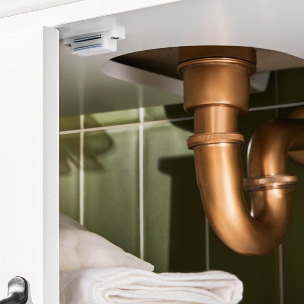 Detailansicht eines Siphons unter einem Waschbecken im Badezimmer, zusammen mit einem Magnetverschluss.