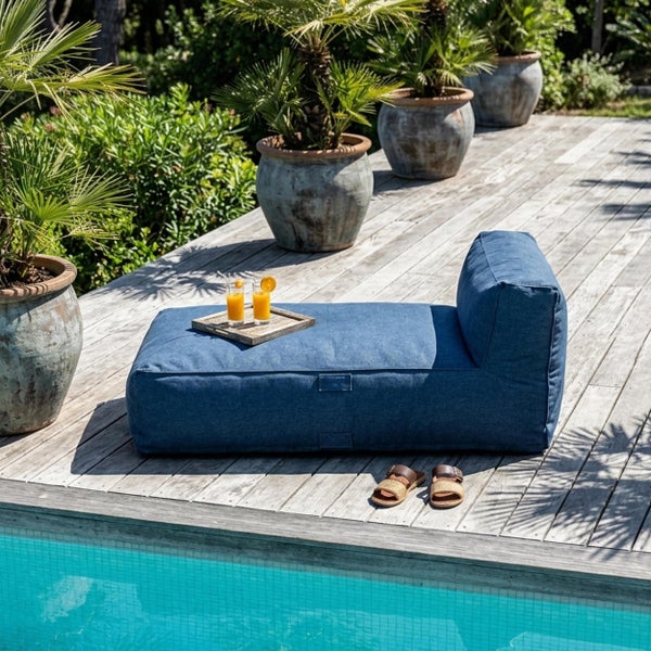 Blaue Outdoor-Sitzsackliege auf einer Holzterrasse am Swimmingpool mit Palmen in Pflanztöpfen.