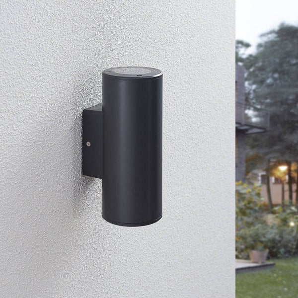 Zylindrische Außenwandleuchte in Schwarz an einer Fassade.