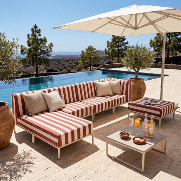 Gestreiftes Lounge Sofa Set mit Beistelltisch und Sonnenschirm auf einer hellen Terrasse an einem Pool. Modernes Design aus Metall und Textil.