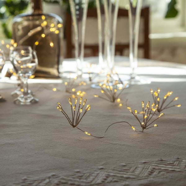 Tischdekoration mit LED-Lichterkette, Gläsern und Flasche