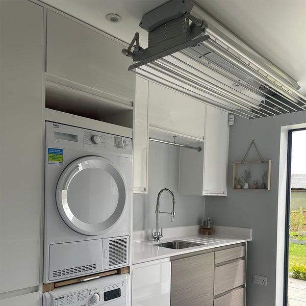 Wäscheraum mit Waschmaschine, Trockner, Spüle, Arbeitsplatte und Wäscheständer an der Decke