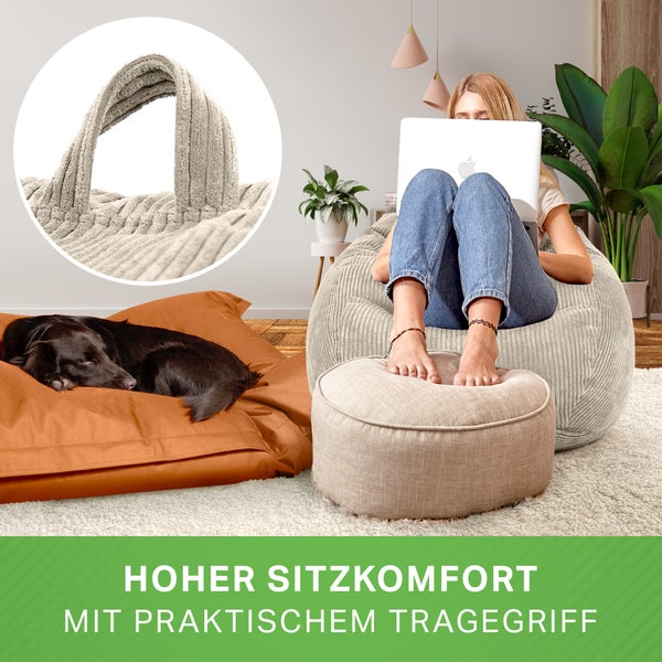 Frau sitzt mit Laptop auf einem Cord Sitzsack mit Tragegriff und Hocker, ein Hund liegt auf einem Kissen