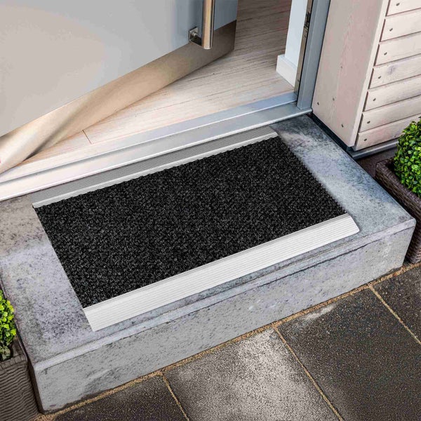 Schmutzfangmatte vor einer offenen Tür auf einer Treppenstufe.