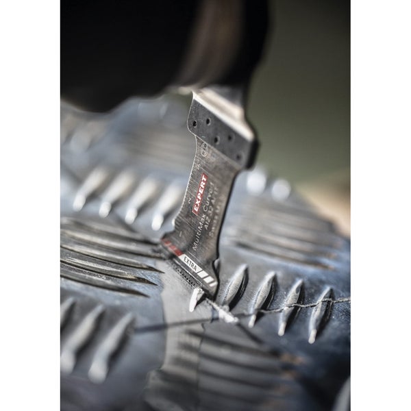 Ein Arbeiter schneidet mit einem Elektrowerkzeug ein Loch in eine Riffelblechwand.