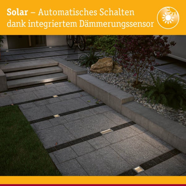 Solarbetriebene Bodeneinbauleuchten in einem modernen, gepflasterten Gartenweg mit Stufen und automatischem Dämmerungssensor.