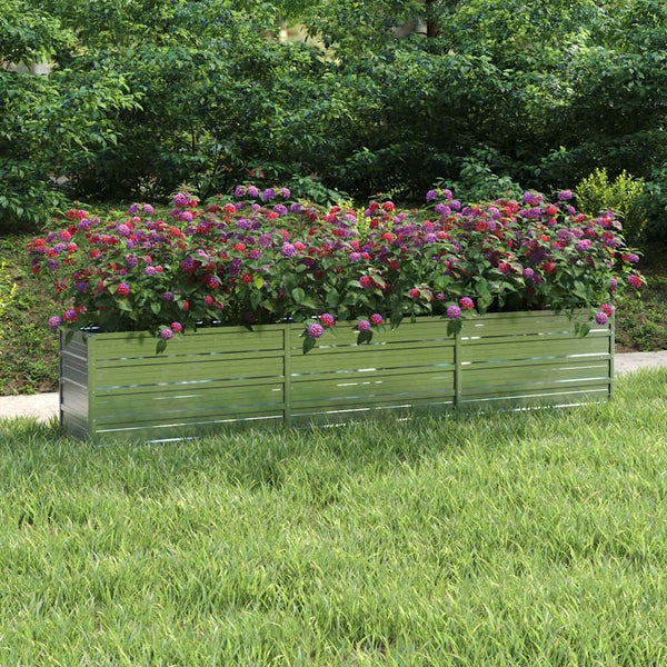 Rechteckiges Hochbeet aus verzinktem Metall mit horizontalen Lamellen, bepflanzt mit lila und roten Blumen in einem Garten.