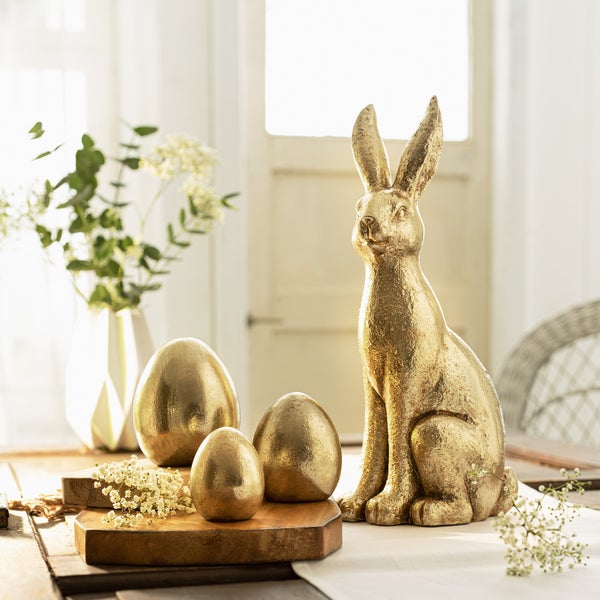 Dekorative Szene mit goldenem Osterhasen und Ostereiern auf einem Tisch