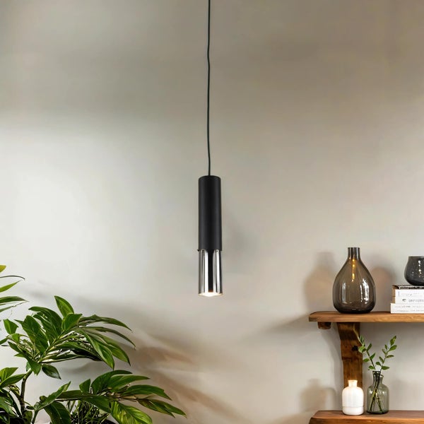 Hängelampe mit zylindrischem Lampenschirm über einem Regal mit Vasen und Büchern