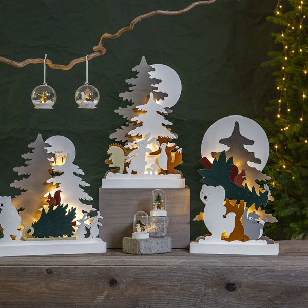 Beleuchteter Baum im verschneiten Garten bei Dämmerung