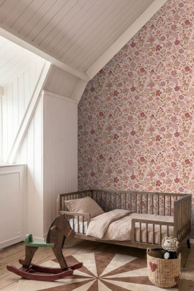 Helle Kinderzimmer-Szene mit floraler Tapete, einem Holzbett und einem Schaukelpferd unter einer Dachschräge mit Holzpaneelen.