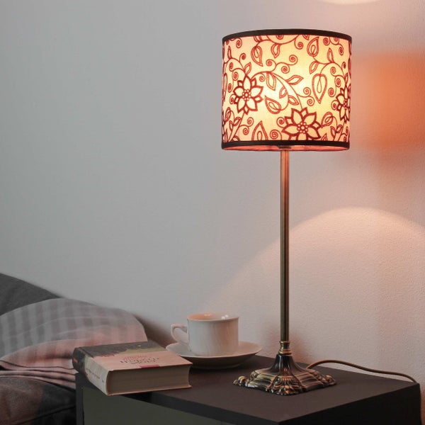 Dekorative Lampe mit Blumendesign auf Nachttisch mit Buch und Tasse