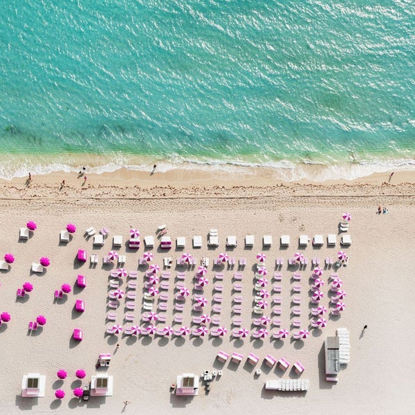 Luftaufnahme eines Strandes mit Liegestühlen und Sonnenschirmen