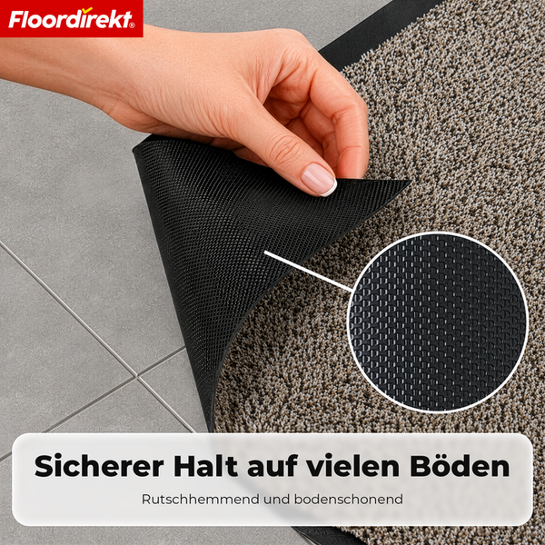 Rutschhemmende Unterseite einer Fußmatte auf Fliesenboden, Floordirekt Logo.
