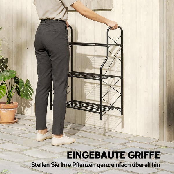 Dreistöckiges Pflanzenregal aus Metall mit integrierten Griffen, das von einer Person auf einer Terrasse getragen wird.