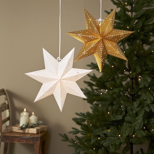 Dekorative Papiersterne, hängend, mit Muster und Weihnachtsbaum im Hintergrund