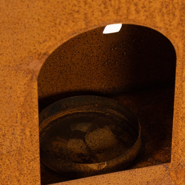 Detailaufnahme eines Metall-Gartenobjekts mit Rostoptik und integriertem runden Halter in einer bogenförmigen Nische.
