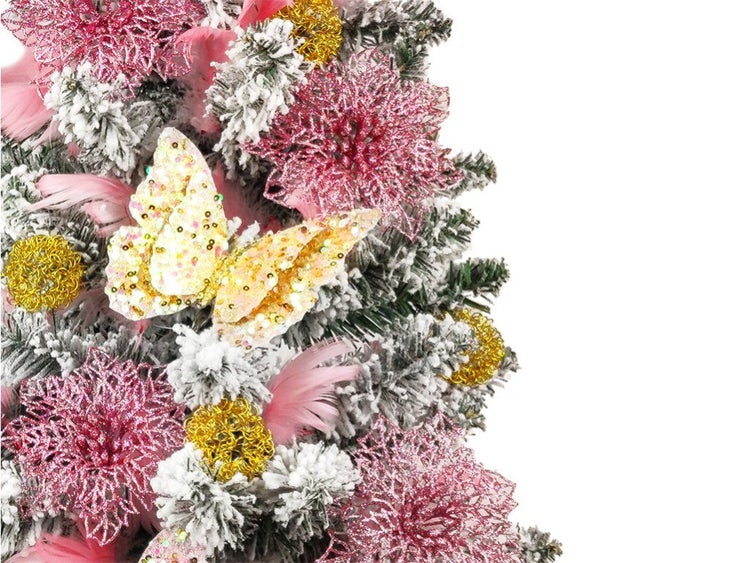 Weihnachtsbaumdekoration mit künstlichen Blüten, Schmetterling und Federn an einem beschneiten Tannenbaumzweig.