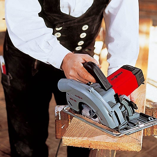 Ein Zimmermann verwendet eine Mafell Handkreissäge, um ein Holzbrett zu sägen.