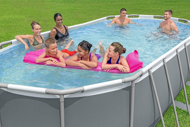 Rechteckiger Aufstellpool mit grauem Metallrahmen und Außenwand, in dem mehrere Personen schwimmen und auf einer Luftmatratze entspannen.