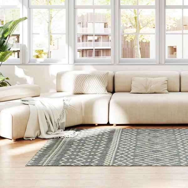 Helles Wohnzimmer mit beige Modulsofa und Flachgewebe-Teppich mit geometrischem Rautenmuster auf Holzfußboden.